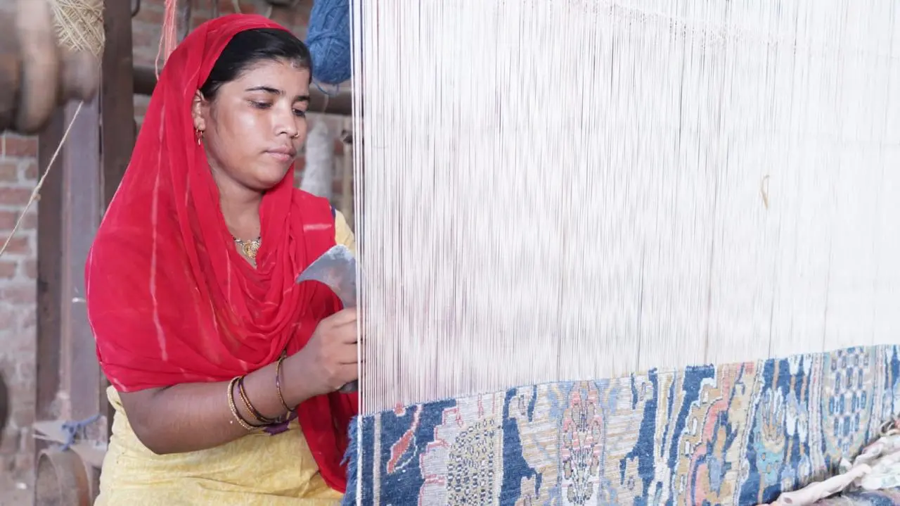 Weaver hand knotting a custom rug on a vertical loom in Jaipur, India
